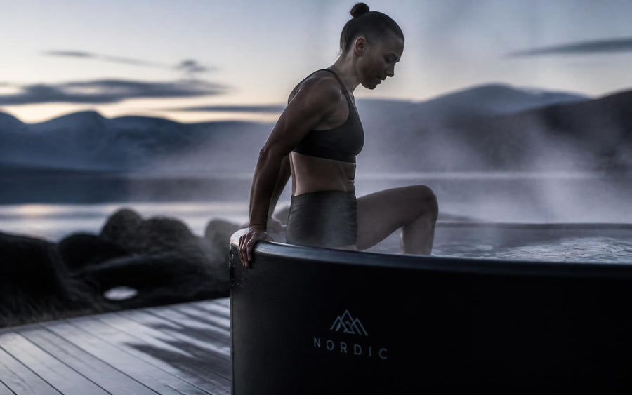 Athlete stepping into a Glacian cold plunge tub at dawn with mist rising